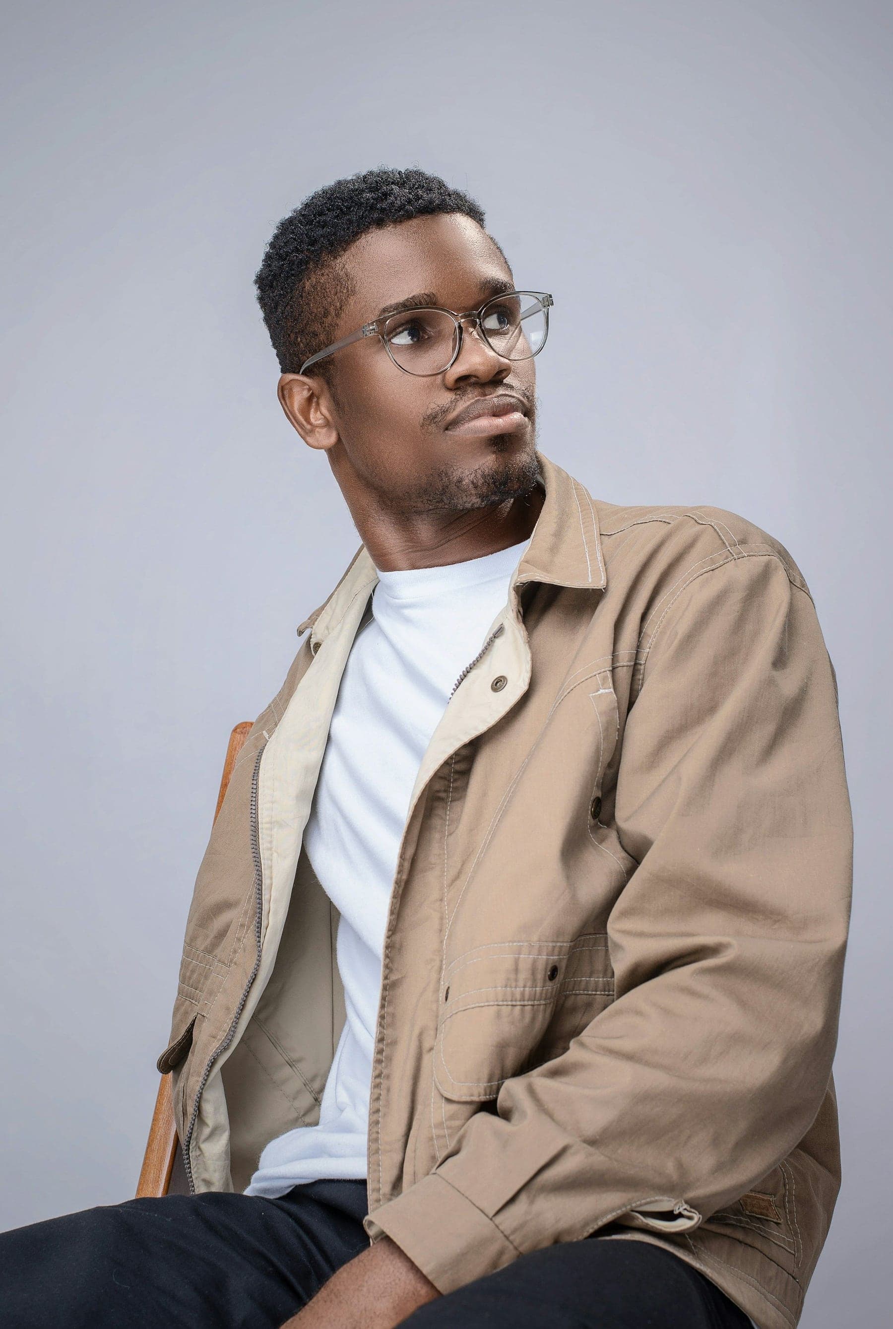 Man in a sand-coloured jacket wearing fine wire-framed glasses