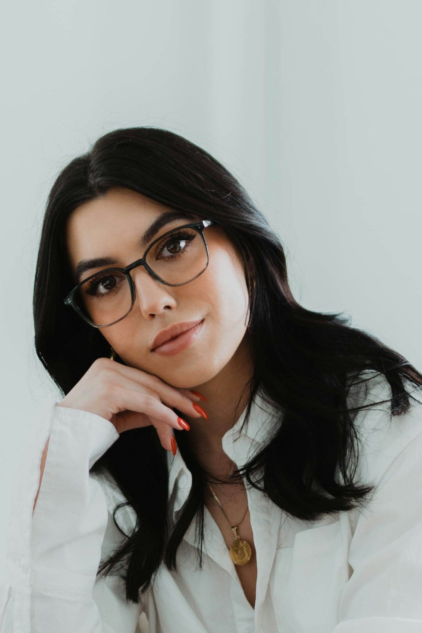 Woman in a white blouse wearing fine dark-framed glasses