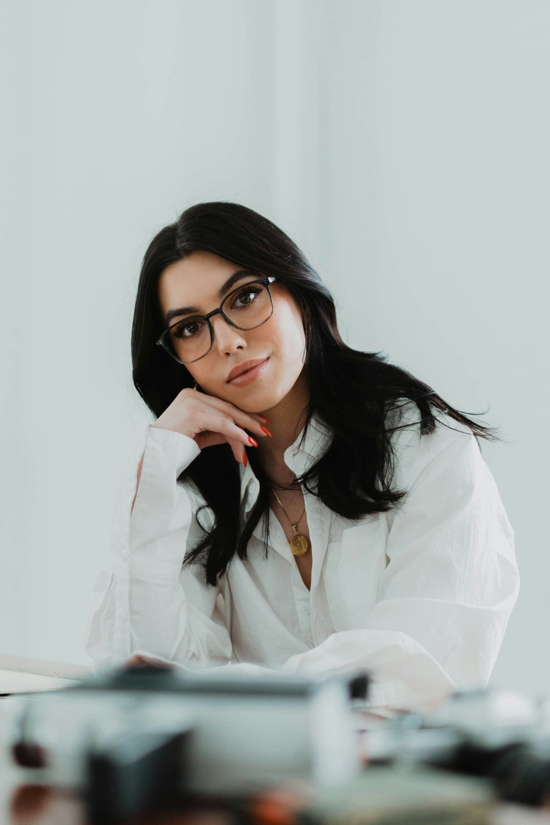 Woman in a white blouse wearing fine dark-framed glasses — the Signature Collection