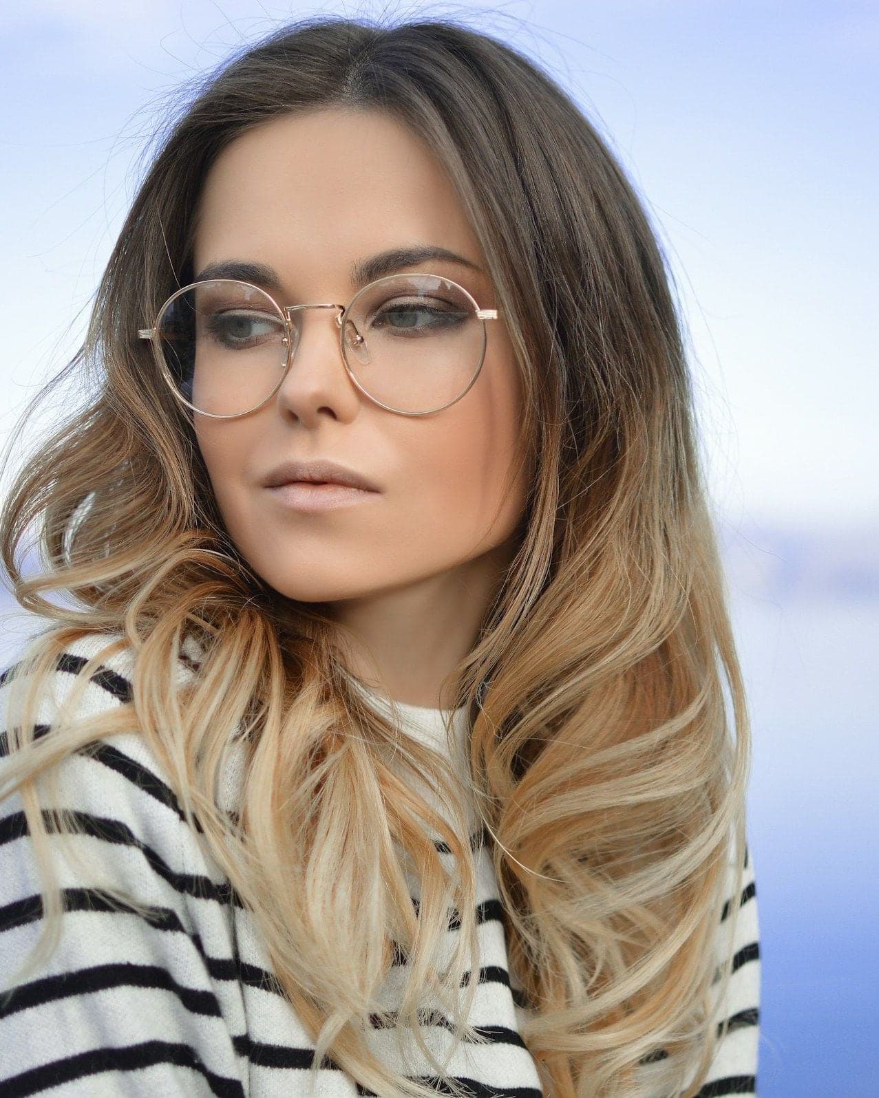 Woman in a striped top wearing round wire-framed glasses